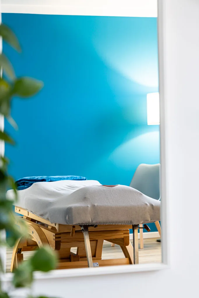 Behandlungsraum mit blauer Wand und Therapieliege