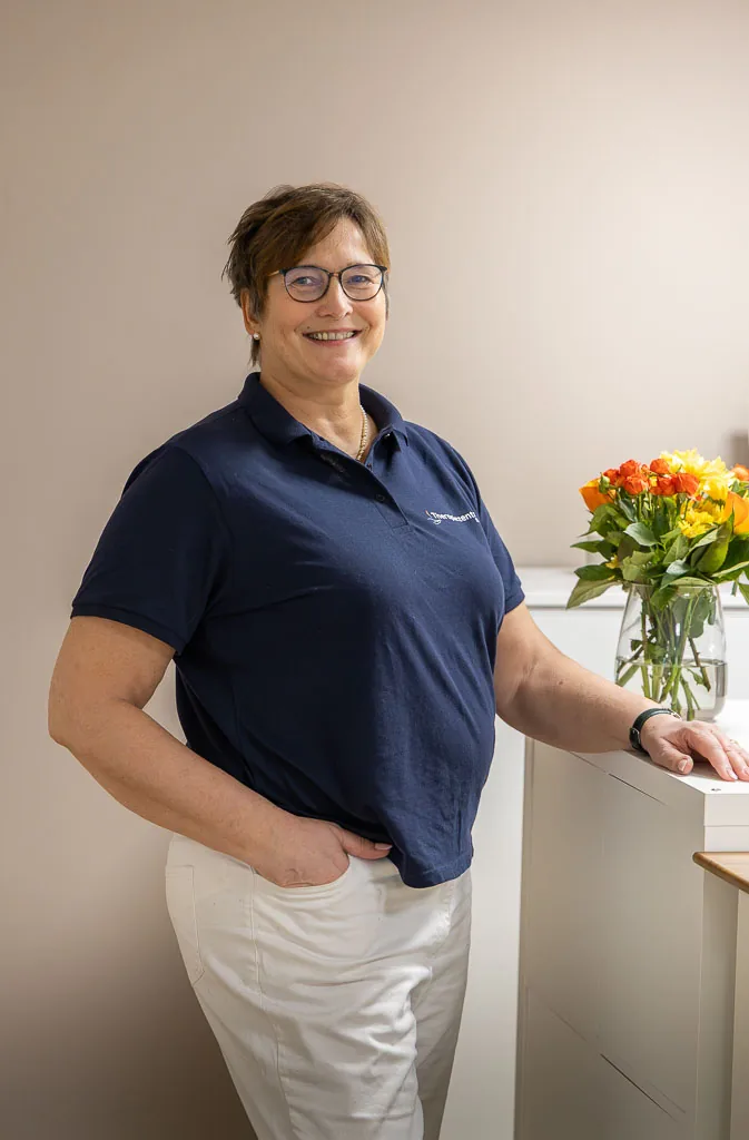 Claudia Barop, Inhaberin des Therapiezentrums, an der Anmeldung mit Blumenstrauß