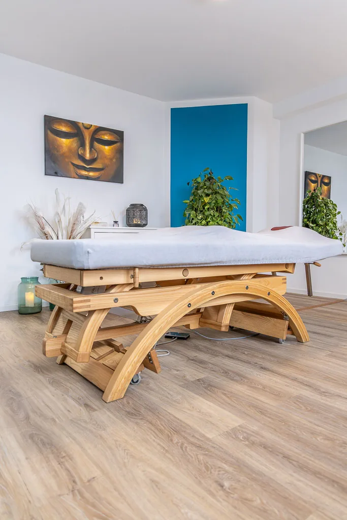 Therapieliege aus Holz im Behandlungsraum mit Buddha-Bild