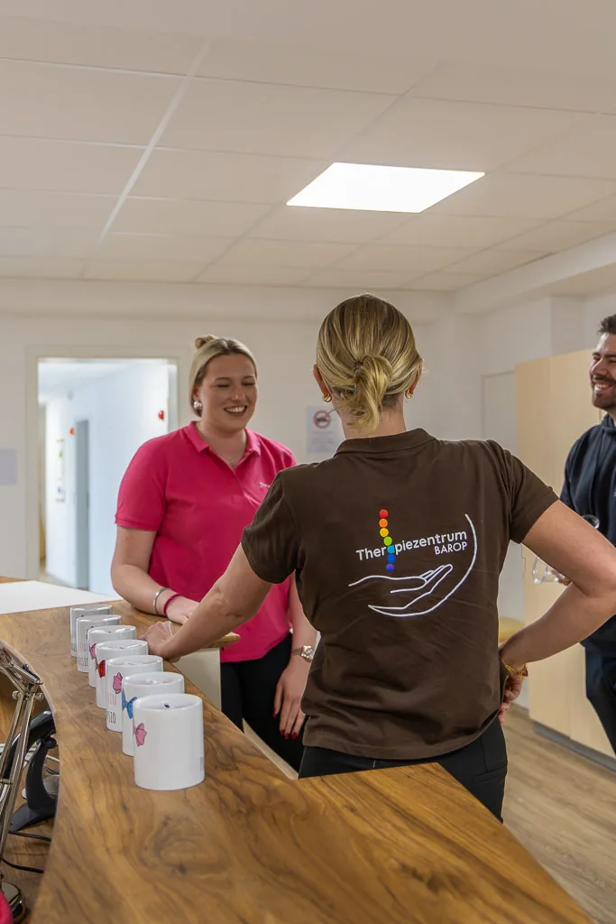 Zwei Mitarbeiterinnen im Gespräch am Empfangstresen des Therapiezentrums